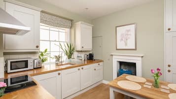 A modern kitchen with white cabinets, a microwave, toaster, and a dining table with placemats.