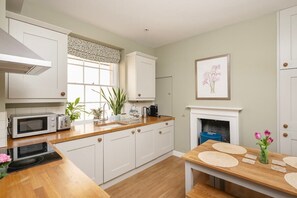 Une cuisine moderne avec des meubles blancs, un four à micro-ondes, un grille-pain et une table à manger avec des sets de table.