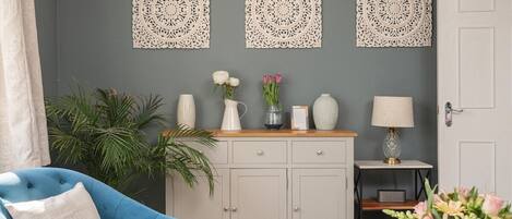 A room with a blue armchair, a white cabinet with decorative items, and a door.