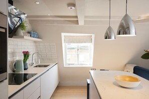 A modern kitchen with white cabinets, a marble countertop, and pendant lighting. - Stylish Georgian Apartment in Centre of Bath (Bath)