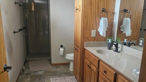 Une salle de bain avec un meuble-lavabo en bois, un grand miroir et un espace douche.