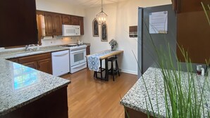 A modern kitchen with wooden cabinets, a microwave, a stove, and a dining area with a table and chairs. - Sleeps 10 close to all attractions! BMSpeedWay, DT, Casino, Holston & Boone Lake (Bristol)