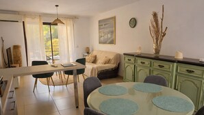 Een moderne woonkamer met een eethoek, een bank, een salontafel en uitzicht op het buitengebied.