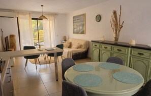 Een moderne woonkamer met een eethoek, een bank, een salontafel en uitzicht op het buitengebied.