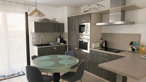 Een moderne keuken met een ronde eettafel, inbouwapparatuur en een hanglamp.