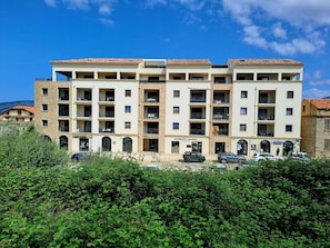 Un immeuble à plusieurs étages doté de balcons, d’un espace de stationnement et d’une devanture visible.