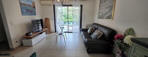 Un salon comprenant un canapé, un téléviseur et un coin repas avec des chaises et une table.
