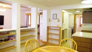 A kitchen with wooden cabinets, a dining table with chairs, and a built-in oven. - Spacious Lakeside house on Long Lake Saint Agatha! (Saint Agatha)