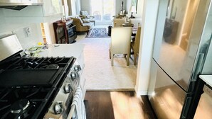 A modern kitchen with a stove, microwave, and refrigerator. There is a dining area with a table and chairs. - Location! Location!  Bright, modern and clean south Oak Bay garden suite. (Victoria)