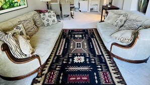 A spacious living room with two sofas, a coffee table, and a large rug. - Location! Location!  Bright, modern and clean south Oak Bay garden suite. (Victoria)