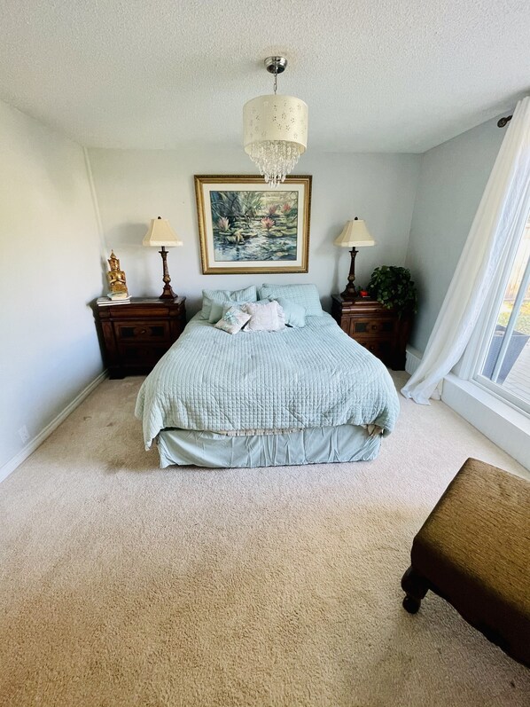 Una camera da letto con un letto, due comodini, un lampadario, un quadro e una finestra con tende.