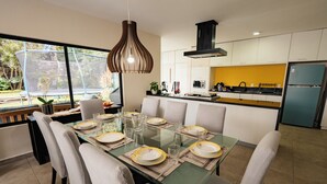 A modern kitchen with a glass dining table set for six, surrounded by chairs.