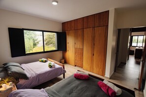Ein modernes Schlafzimmer mit zwei Betten, einem Holzschrank und einem großen Fenster.