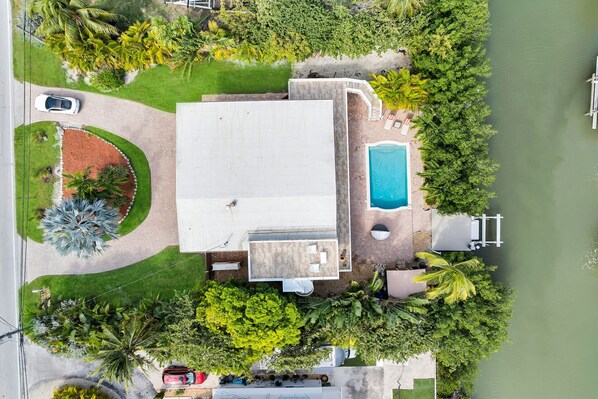 An aerial view of a property with a swimming pool, a covered patio, and a driveway. - Pet Friendly! Ocean Views, Pool & Dock | Walk to Sombrero Beach 🏖️ (Marathon)