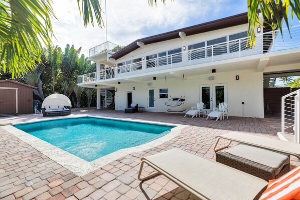 A two-story house with a swimming pool, outdoor seating, and a covered patio area. - Marathon Beach House | Pool, Dock & Ocean Views (Marathon)