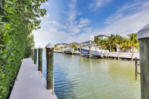 A marina with boats docked, a wooden walkway, and houses in the background. - Pet Friendly! Ocean Views, Pool & Dock | Walk to Sombrero Beach 🏖️ (Marathon)