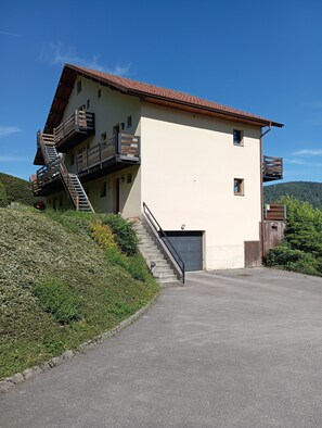 A two-story building with a sloped roof, a staircase leading to the upper floor, and a garage.