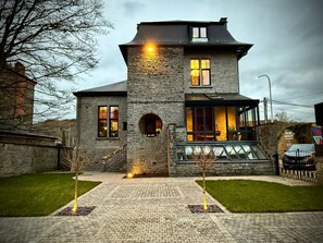 A stone house with a large front porch, a staircase, and a car parked nearby. - Exceptional villa on the banks of the Meuse. 4 bedrooms, garden, jacuzzi, brazier (Profondeville)