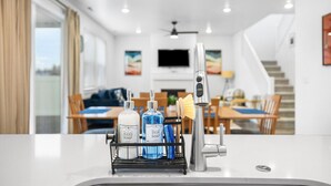 Una cocina moderna con un grifo de acero inoxidable, un dispensador de jabón y una botella de detergente para platos sobre la encimera.