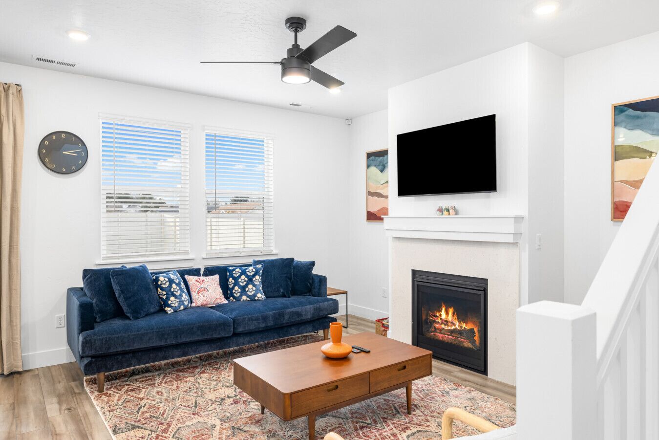 A living room with a blue sofa, a wooden coffee table, a fireplace, and a TV mounted above it.