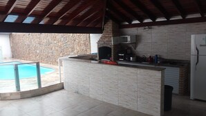 Une cuisine avec un mur en pierre, une piscine et un plafond avec des poutres en bois.