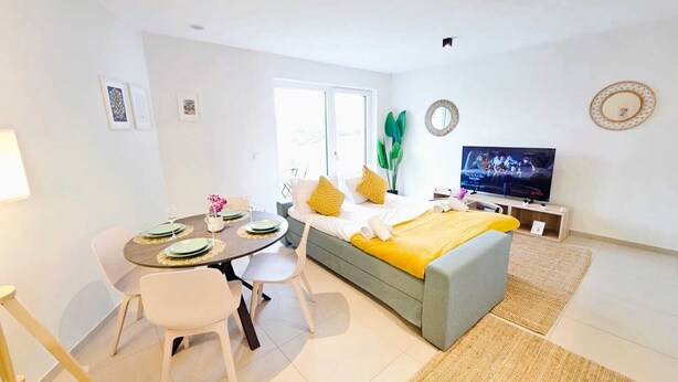A modern, well-lit room with a dining table, chairs, a sofa, a TV, and a window. - Warm&Bright 1BR w terrace&parking (Luxembourg City)