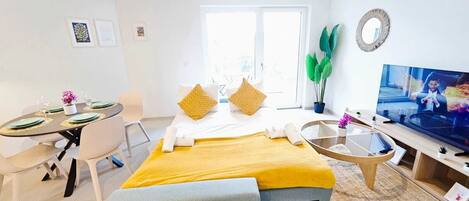 Une chambre d’hôtel avec un lit, une télévision, un bureau avec des chaises et une fenêtre.