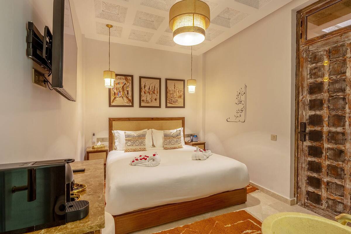 A hotel room with a large bed, a television, a desk with a computer, and a decorative door.