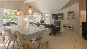 Un vaste espace de vie comprenant une grande table à manger, des sièges confortables, un téléviseur à écran plat et un coin cuisine.