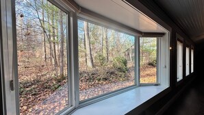 Una habitación con amplios ventanales con vistas a una zona boscosa.