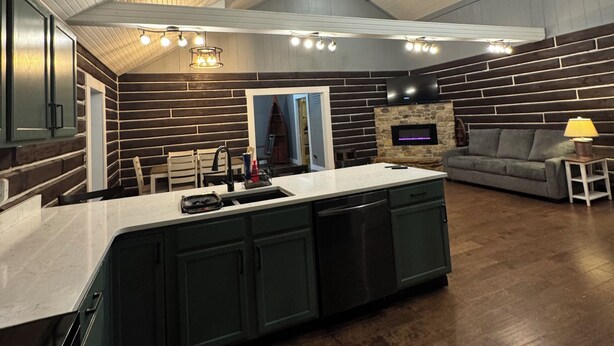 Una cocina moderna con una isla central, armarios oscuros y una pared decorativa de piedra.