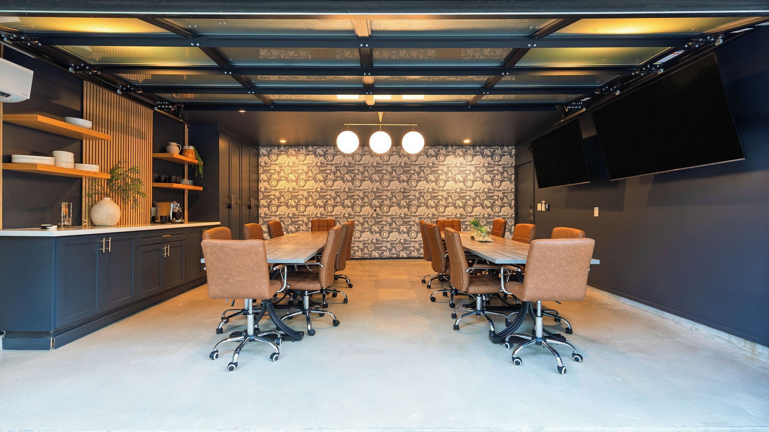 A conference room with a long table, six chairs, and a patterned wall.