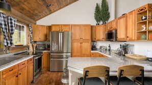 Eine moderne Küche mit Holzschränken, Edelstahlgeräten und einer Arbeitsplatte aus Granit.
