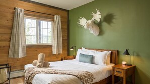 Ein gemütliches Zimmer mit einem hölzernen Bett, einer grünen Wand und einer Dekoration mit Hirschgeweih.