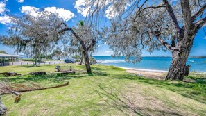 A park with a bench, a picnic table, and a view of the ocean.