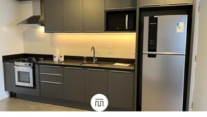 A modern kitchen with stainless steel appliances, grey cabinetry, and a built-in microwave. - Paraíso na Gamboa - Garopaba - SC (Garopaba)