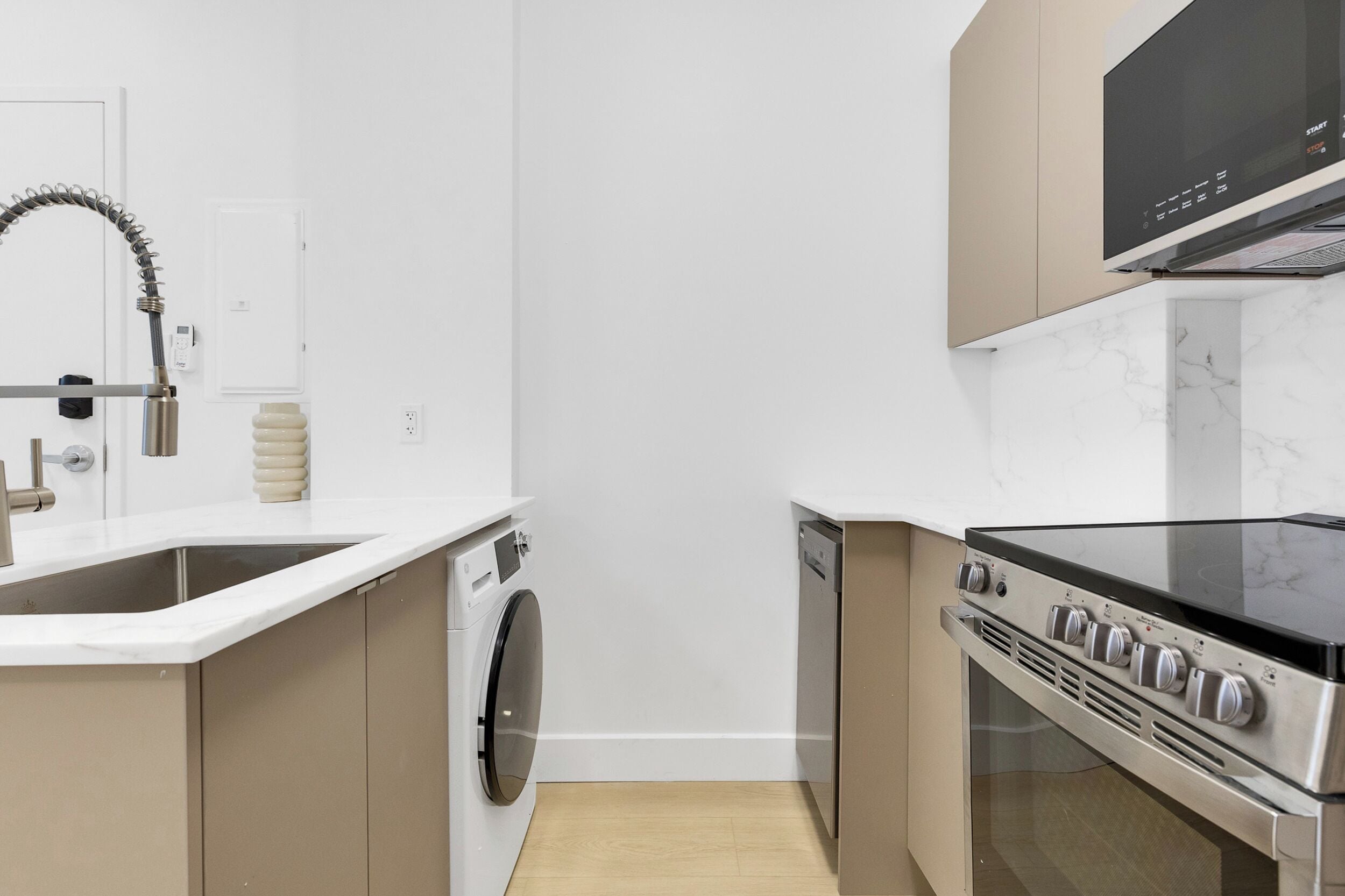 A compact kitchen with a washing machine, dishwasher, and a stove.