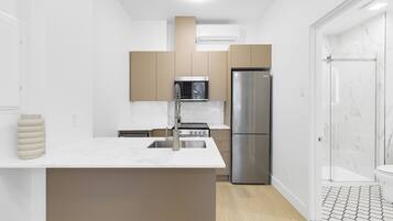 A modern kitchen with a central island, stainless steel appliances, and a walk-in shower with marble tiles.
