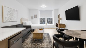 Una stanza moderna e luminosa con un letto, un divano, un tavolo da pranzo e una grande finestra.