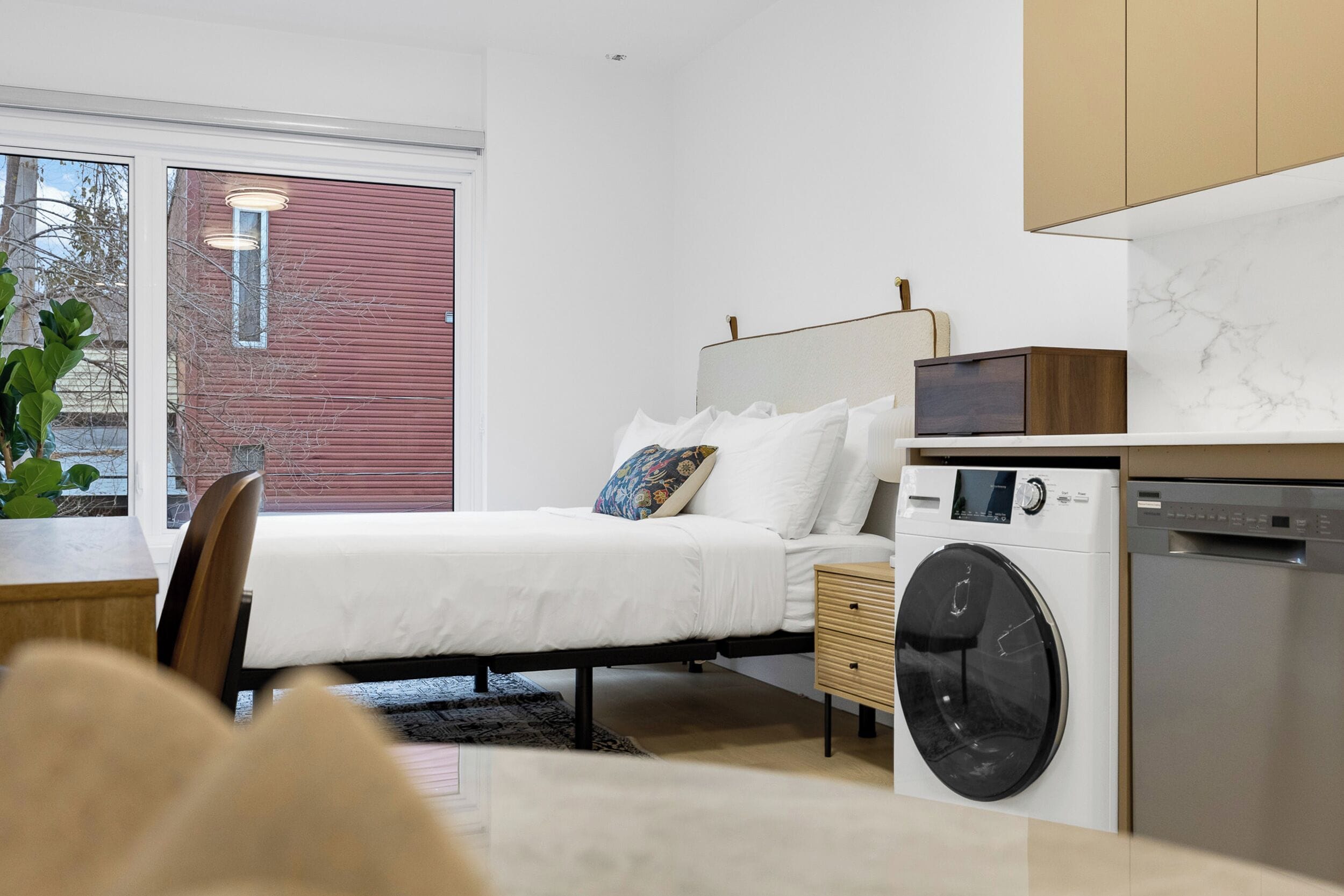 Ein modernes Schlafzimmer mit Bett, Nachttisch und Waschmaschine.