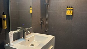Een moderne badkamer met een witte wastafel, een spiegel en een douchehoek.