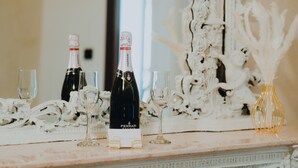 A marble table with two bottles of Ferrari wine, two glasses, and a small yellow vase.