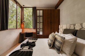 Une chambre à coucher avec un lit, une fenêtre, une armoire et une vue sur les arbres.