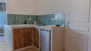 Une cuisine compacte avec un meuble en bois, un lave-vaisselle et un crédence recouverte de carreaux verts.