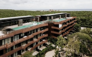 A multi-story hotel with a rooftop pool, balconies, and a view of the sea. - The Chloe Ocean Views Jacuzzi Close to Beach! (Tulum)