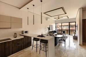 A modern kitchen with a central island, bar stools, and a dining area with a view. - The Chloe Ocean Views Jacuzzi Close to Beach! (Tulum)