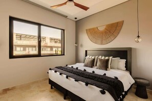 A bedroom with a large window, a ceiling fan, a bed with a headboard, and a wall-mounted light fixture. - The Chloe Ocean Views Jacuzzi Close to Beach! (Tulum)