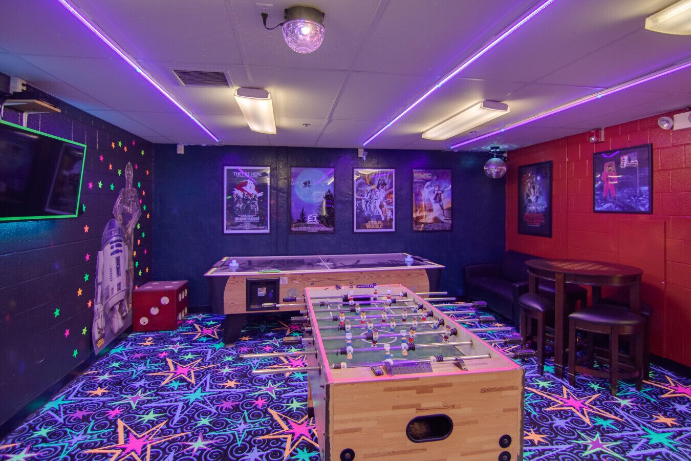 Una habitación con mesa de fútbol de mesa, dardos y una pared temática de Star Wars.