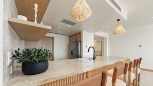 Una cocina moderna con encimera de mármol, taburetes de madera y lámparas colgantes.