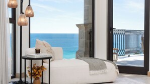 Una habitación moderna con un sofá blanco, una mesita auxiliar con un libro y vistas al océano.